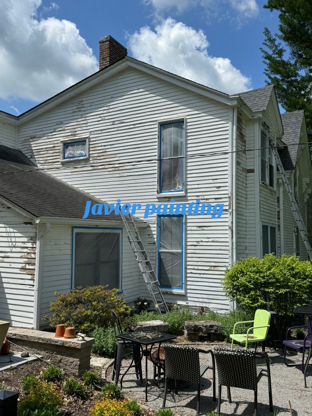 Historic white farmhouse exterior before repainting, showing worn siding