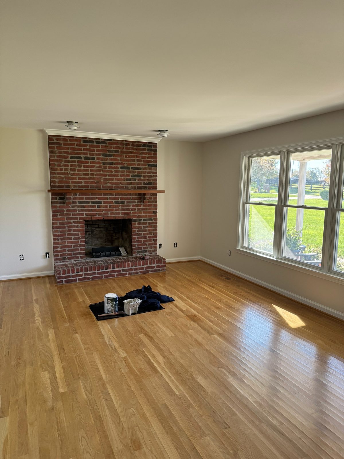 Freshly painted living room with brick fireplace and hardwood floors