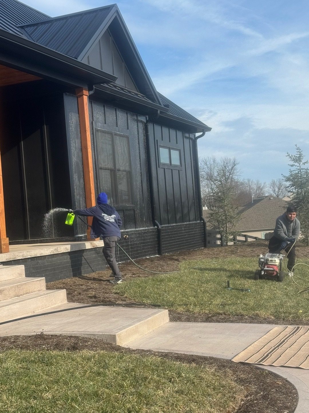 Javier Painting crew member pressure washing a modern black home exterior