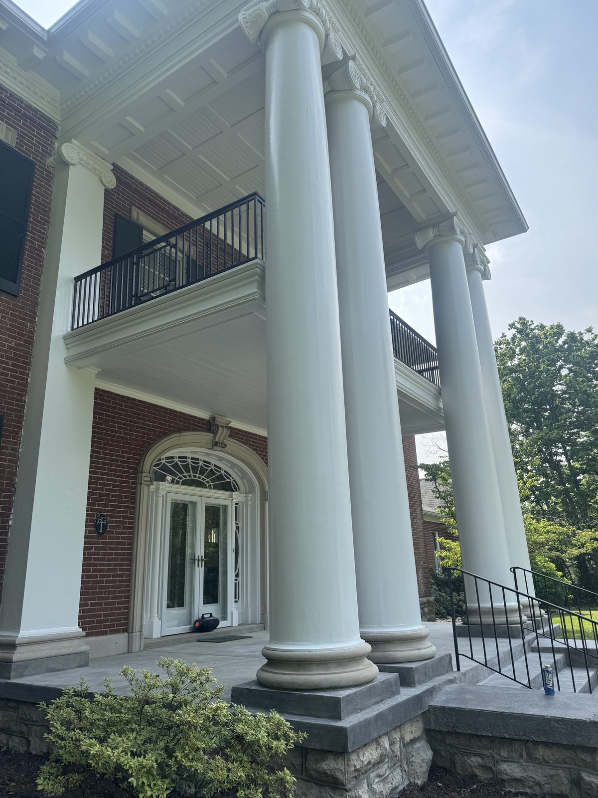 Large white columns and balcony freshly painted on a historic brick estate home
