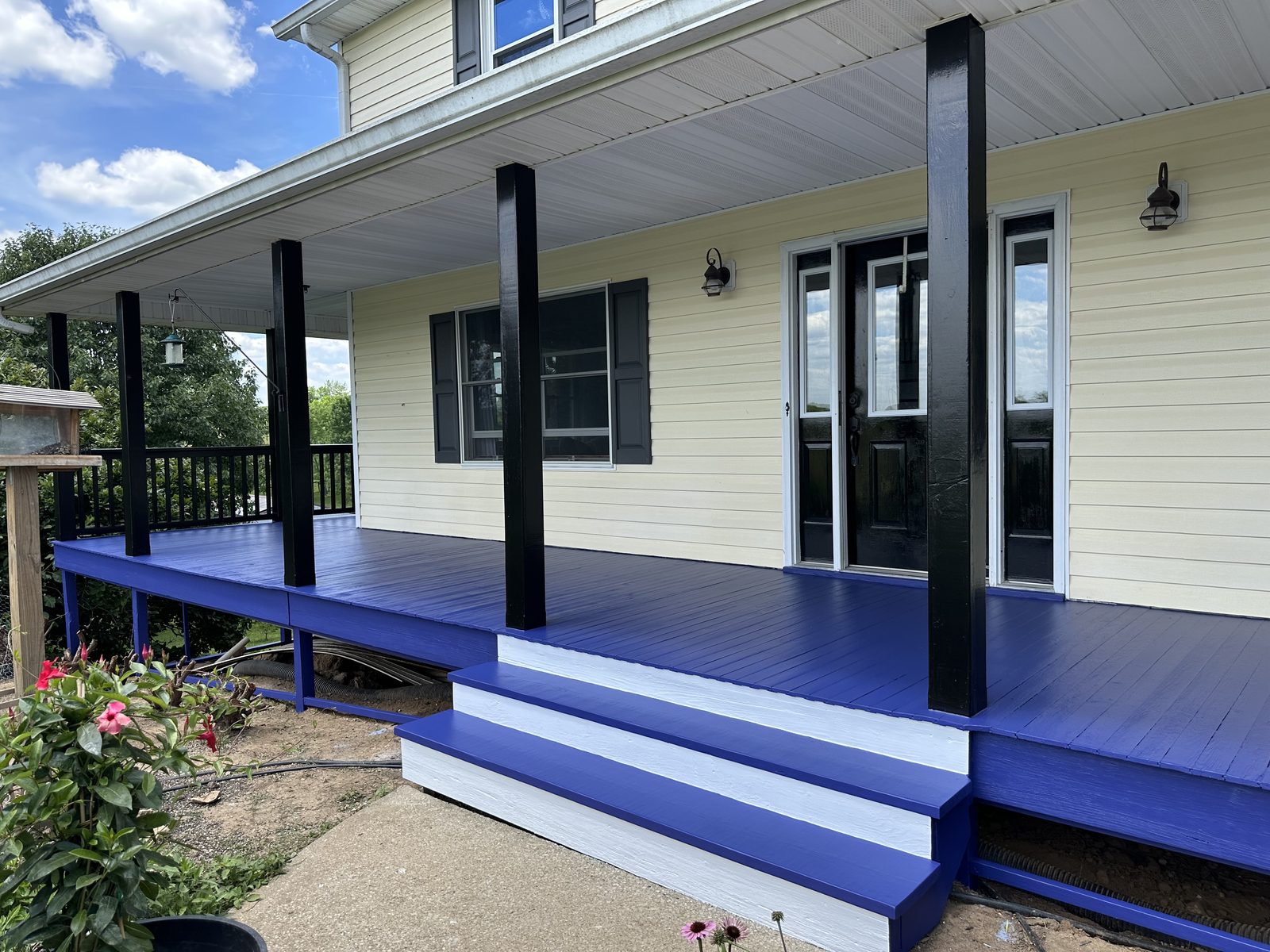Covered front porch and columns freshly painted a bold blue with black trim