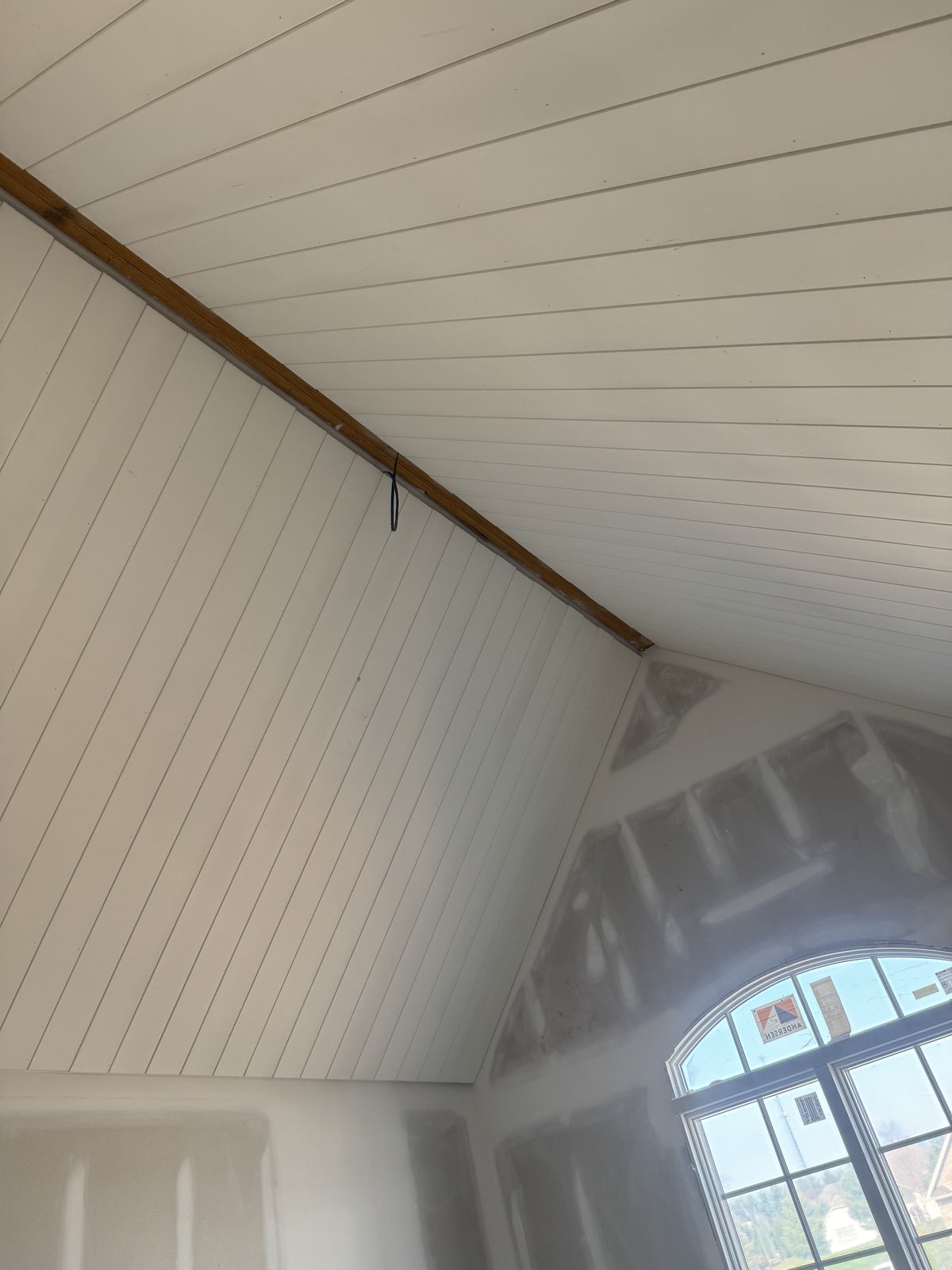 Vaulted shiplap ceiling and wall trim freshly painted white in a new construction home