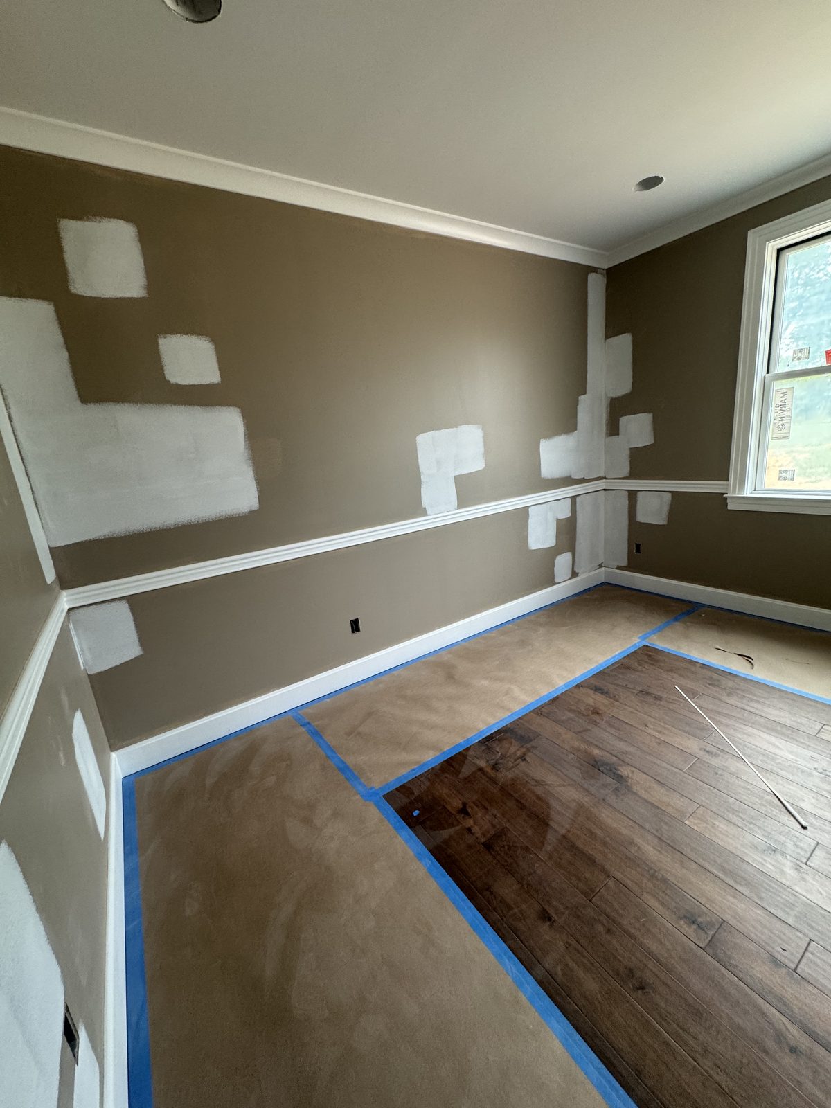 Interior wall with drywall patches primed and taped off, ready for painting