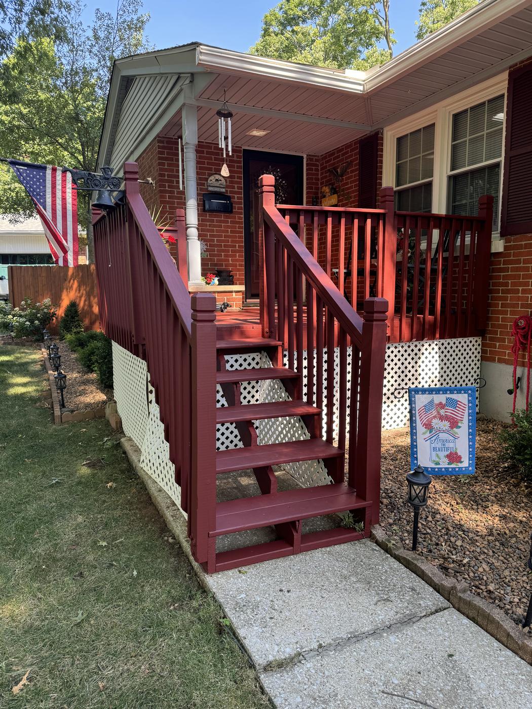Wood porch stairs and railing freshly stained a deep red