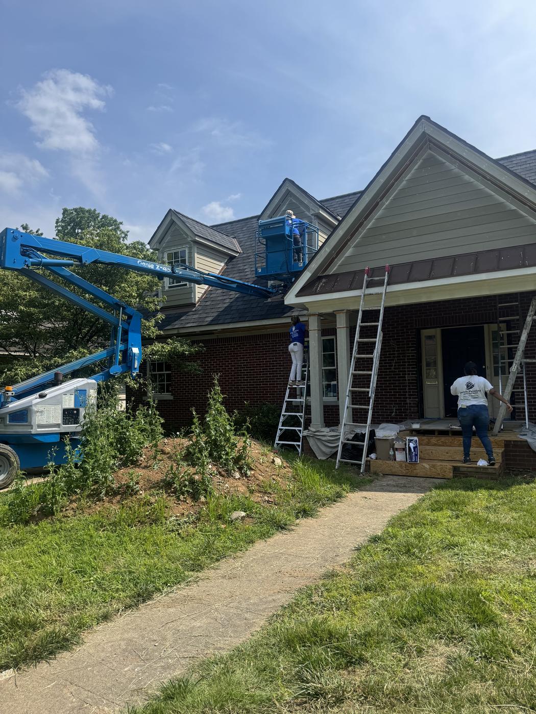 Crew on ladders repainting a home exterior roofline and trim