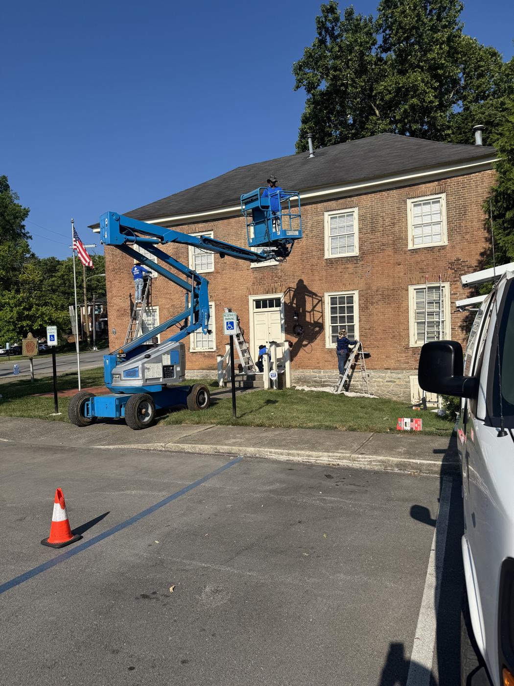 Lift equipment painting a multi-story brick commercial building