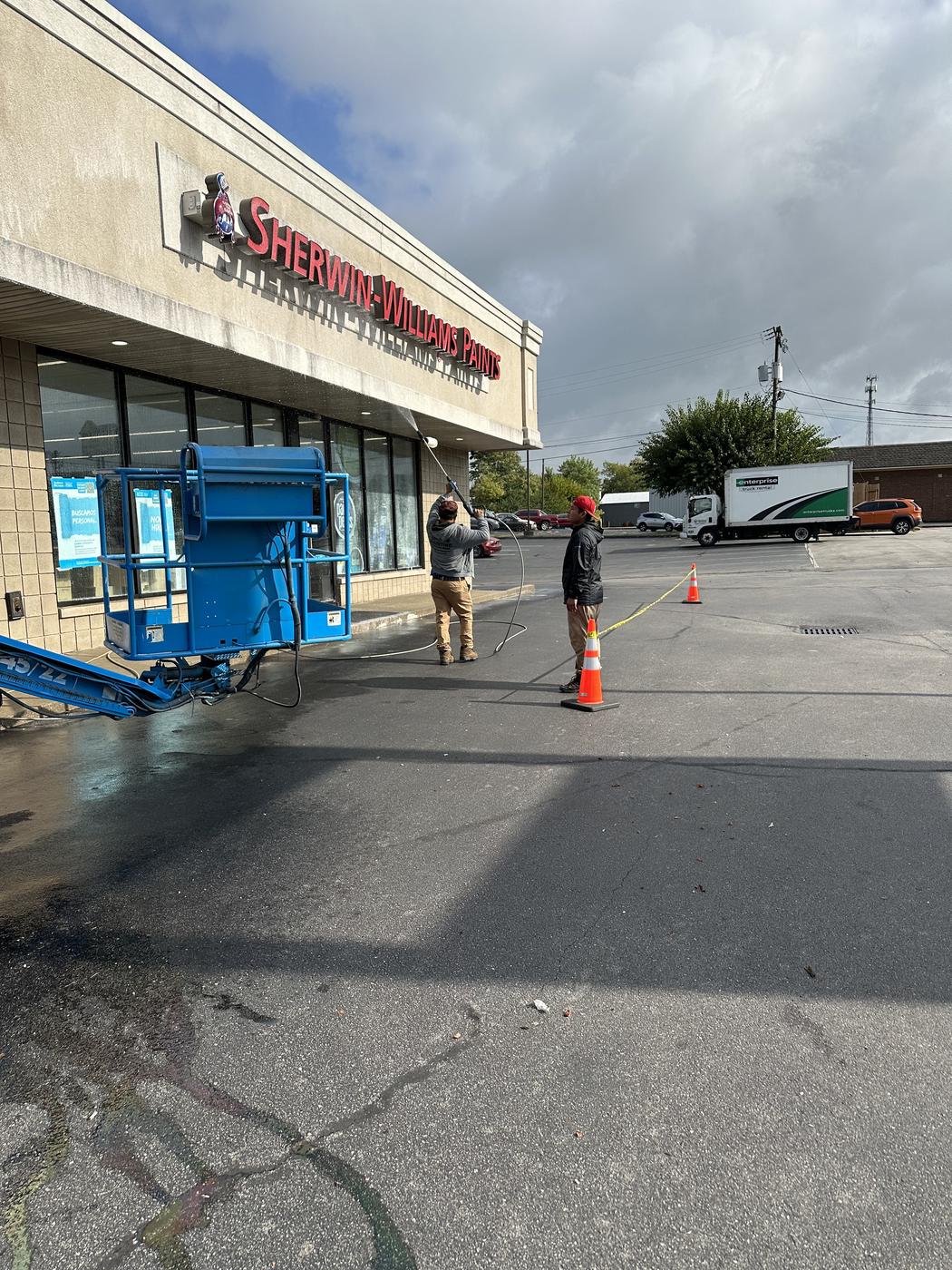 Lift equipment painting the exterior of a retail storefront