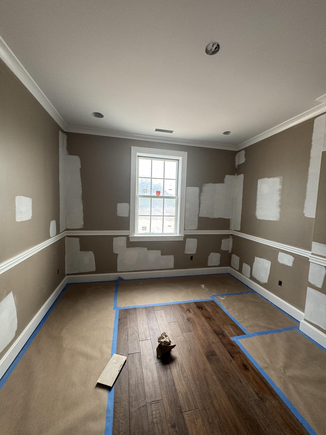 Room prepped with painter's tape and floor protection before painting