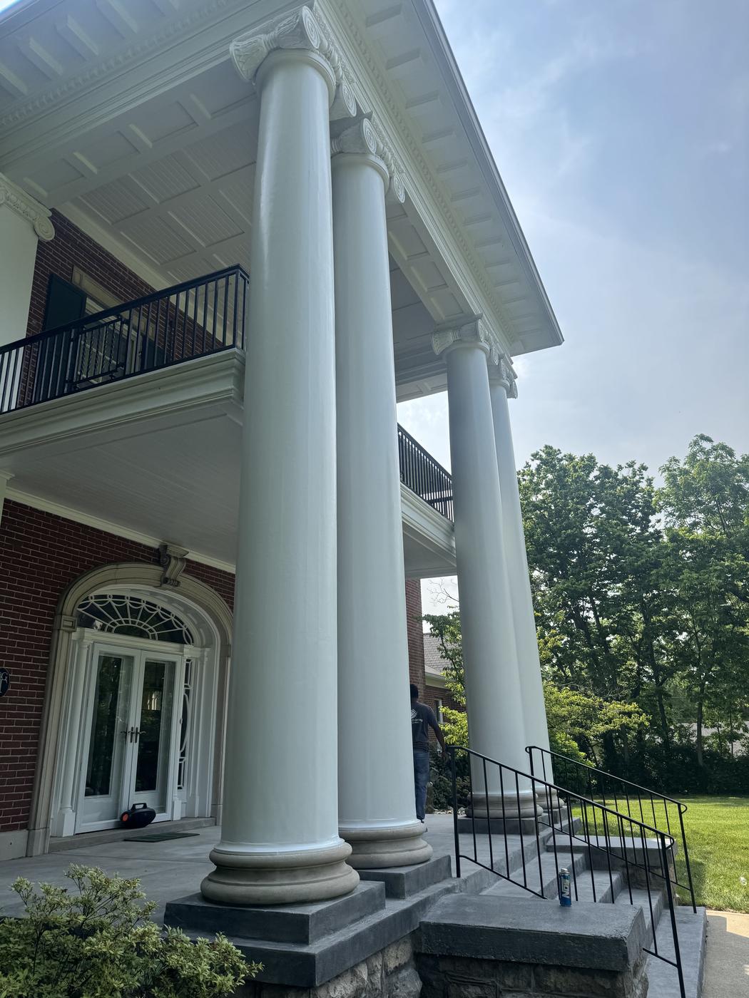 Grand columns and balcony of a historic brick estate home, second angle