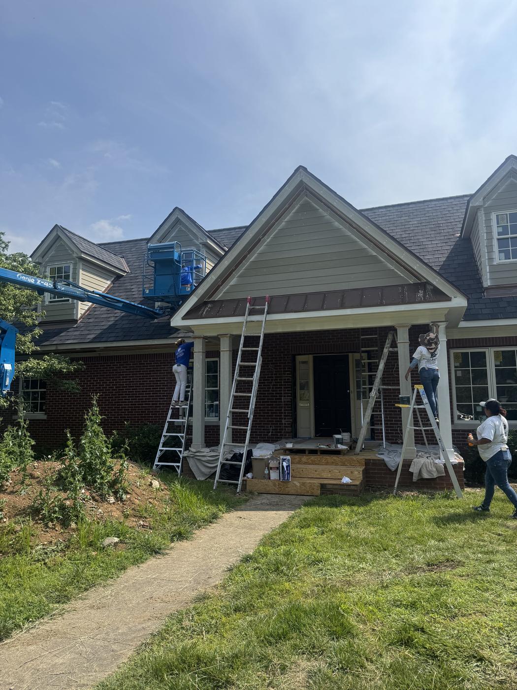 Crew and lift equipment painting a large home exterior gable