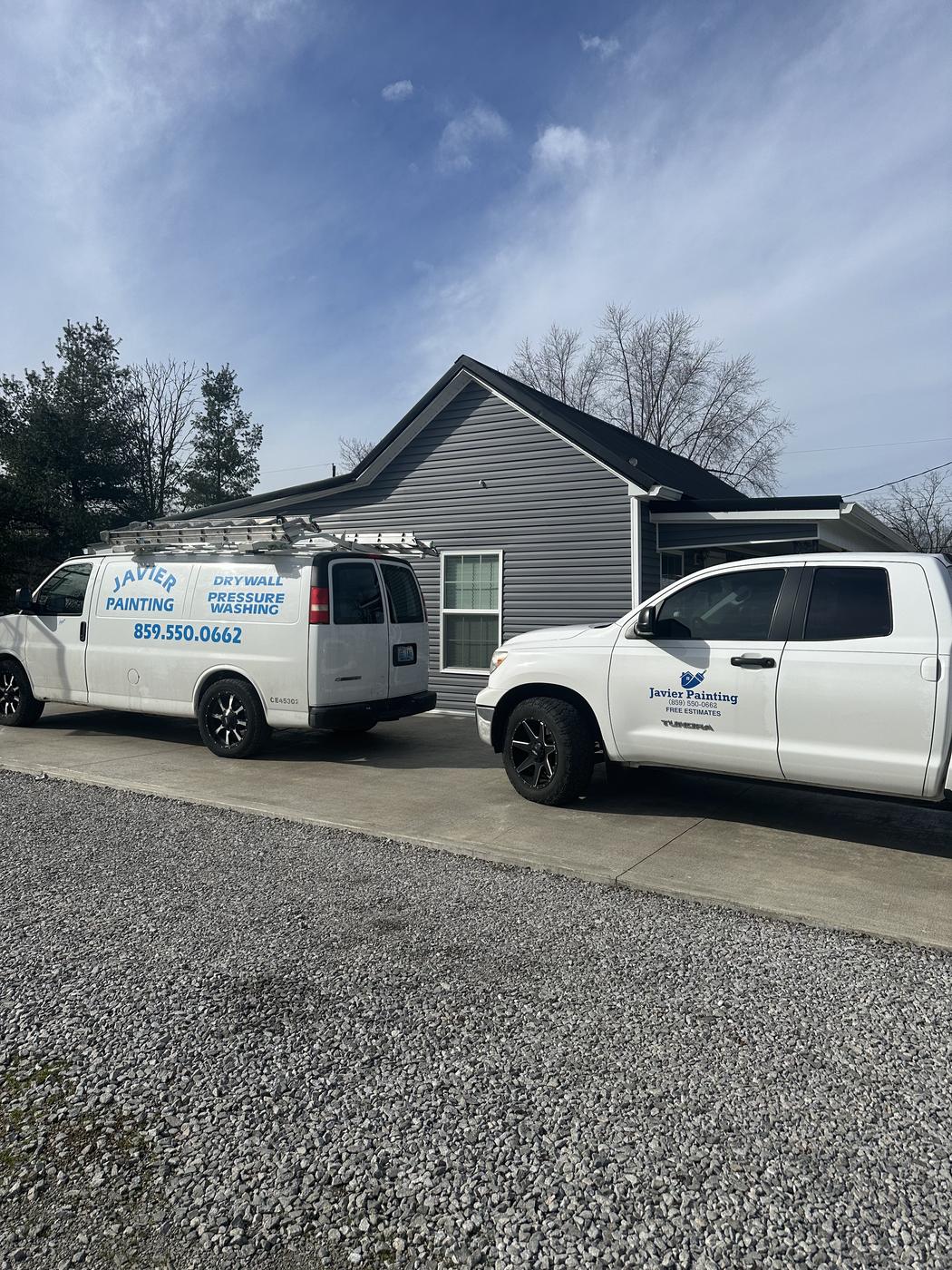 Two Javier Painting vans parked at a new construction site