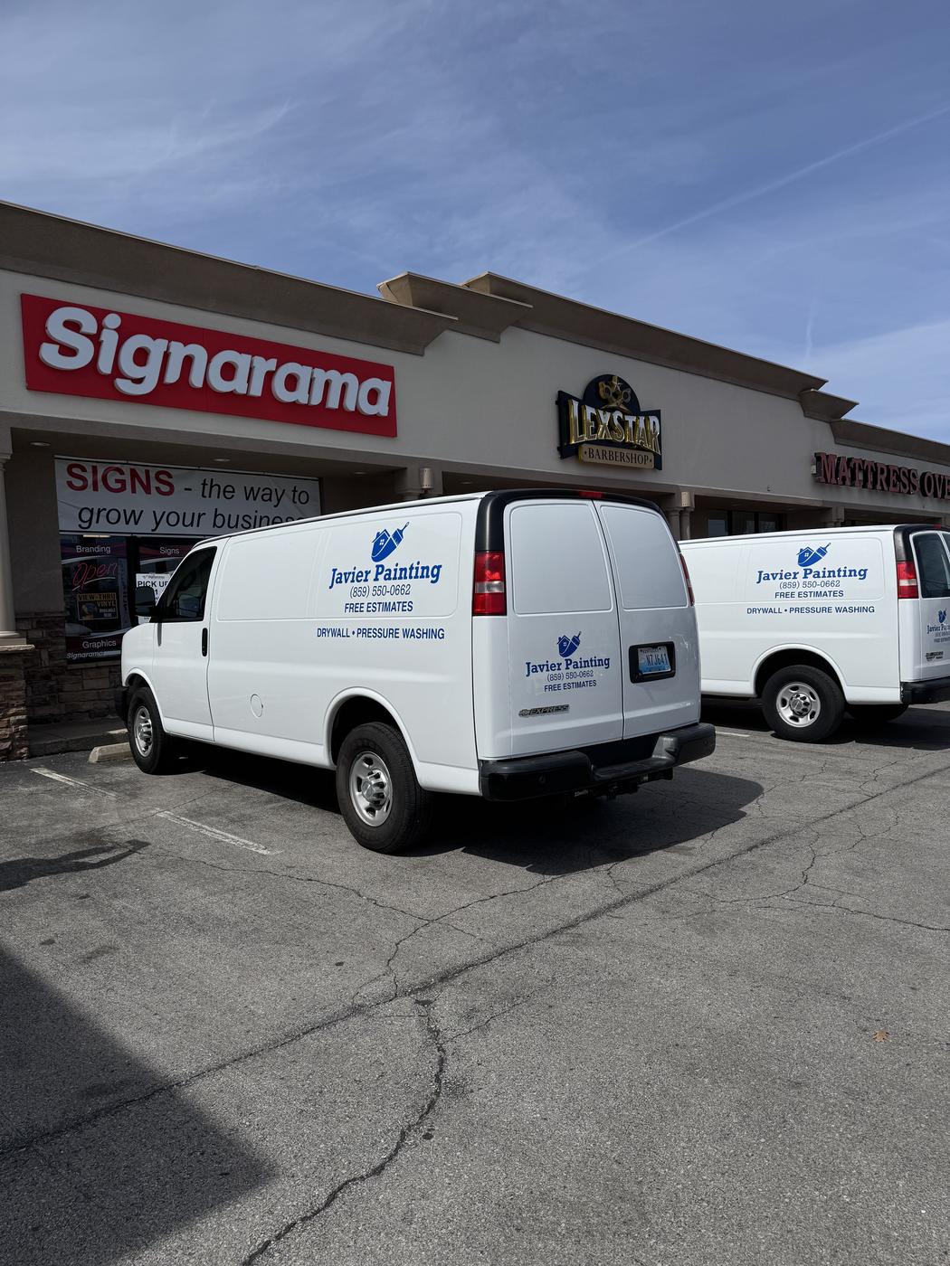 Two Javier Painting vans parked at a shopping plaza job site