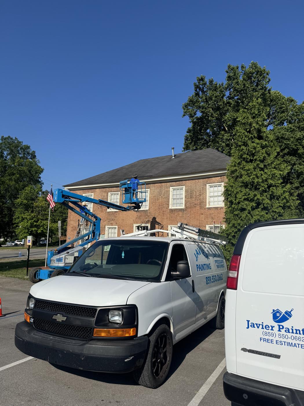 Company van and lift equipment staged at a brick commercial building